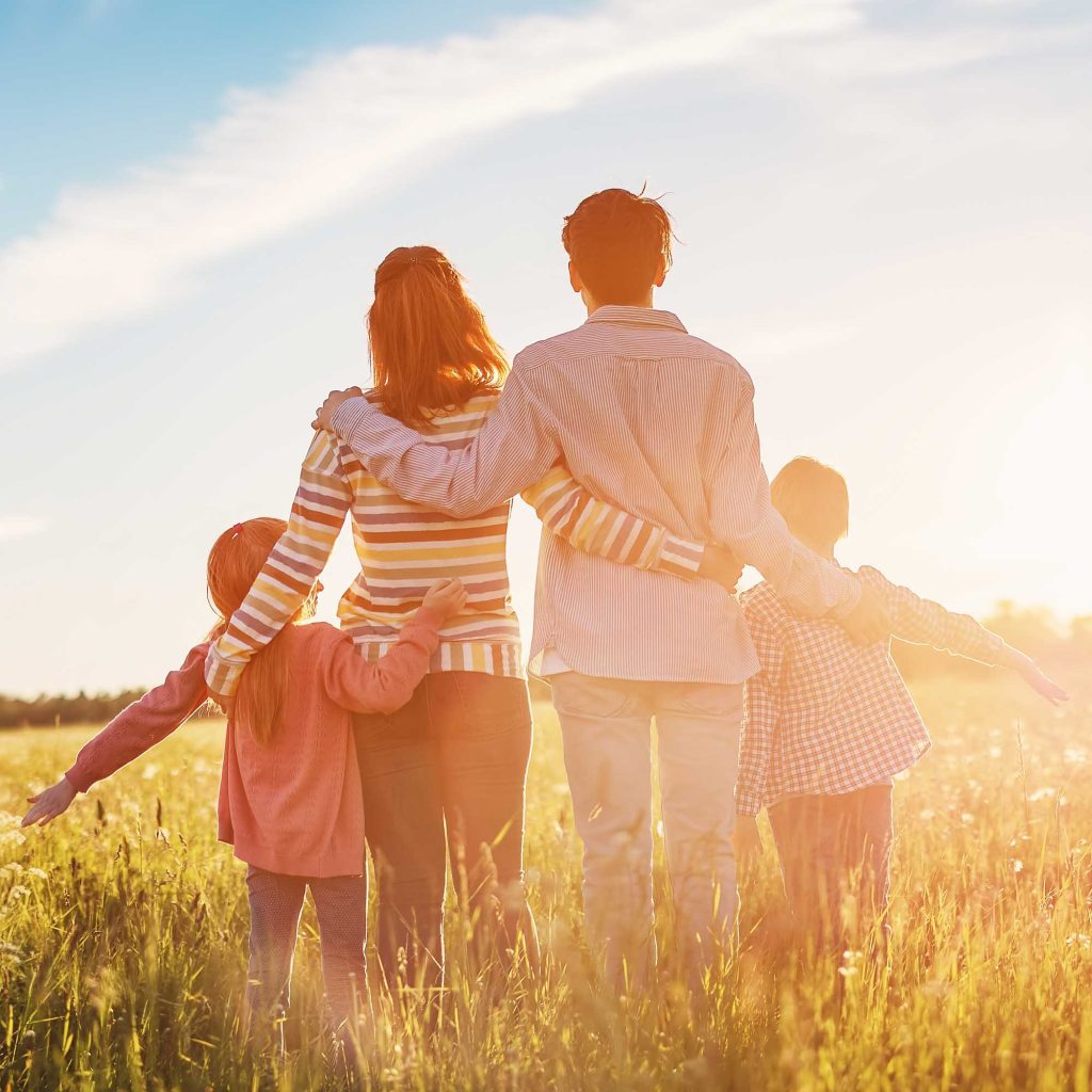 A family walks in a field into the sunset
