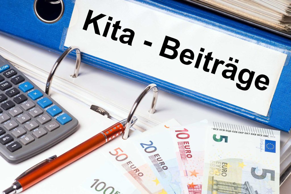 Ein Ordner mit der Aufschrift „Kita-Beiträge“, ein Taschenrechner, ein Stift und etwas Geld