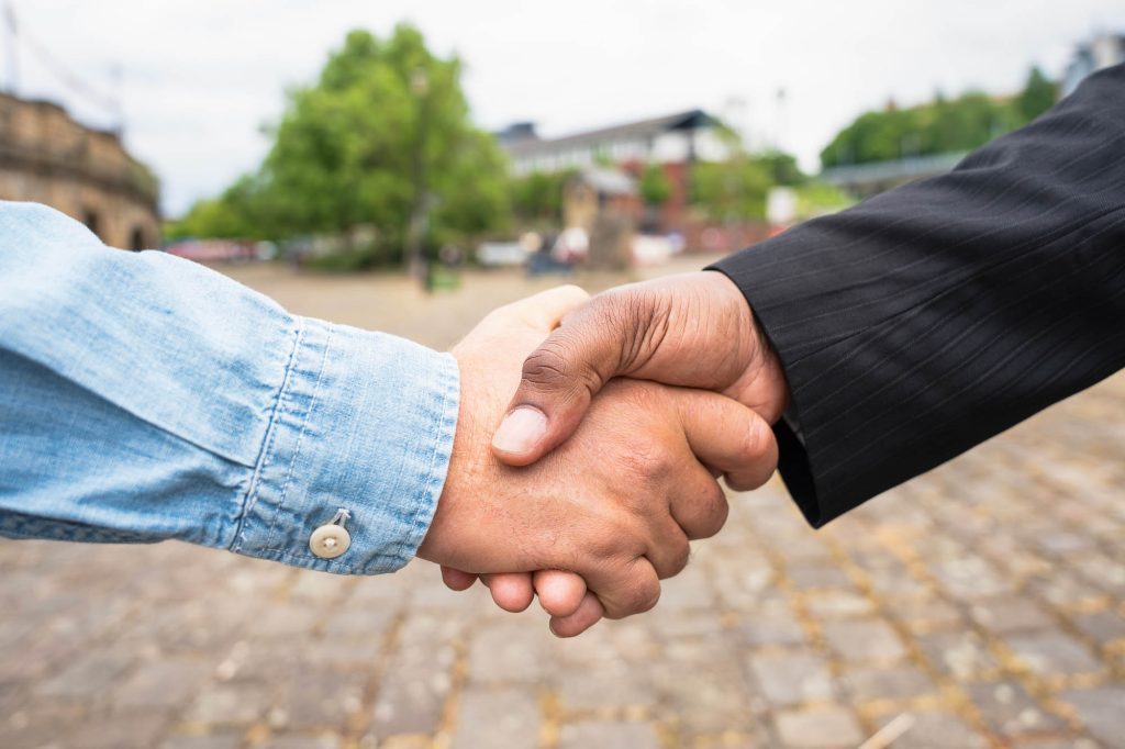 Zwei Hände, die sich schütteln. Eine weiß, eine dunkler.